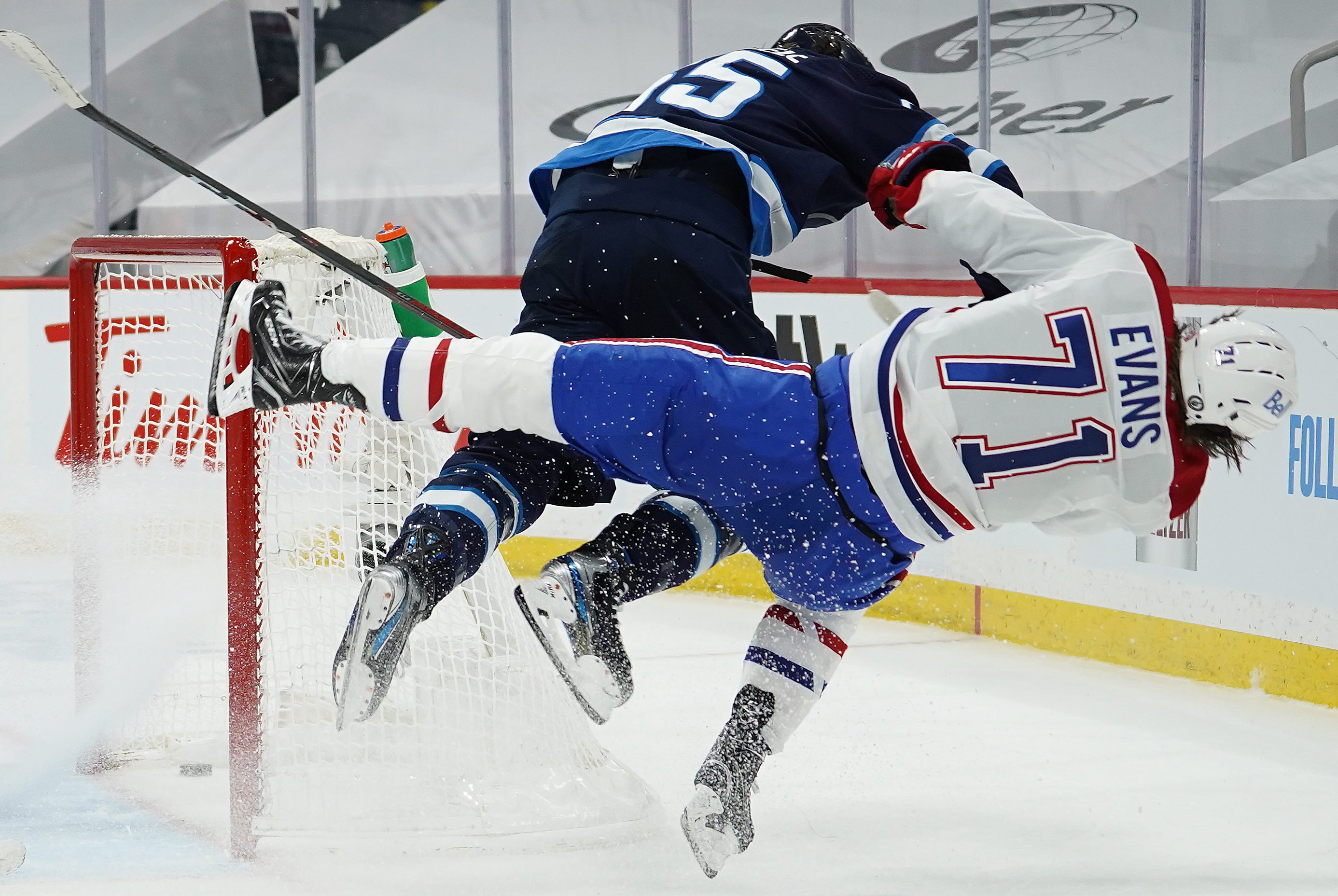 Jake Evans is checked hard by Mark Scheifele