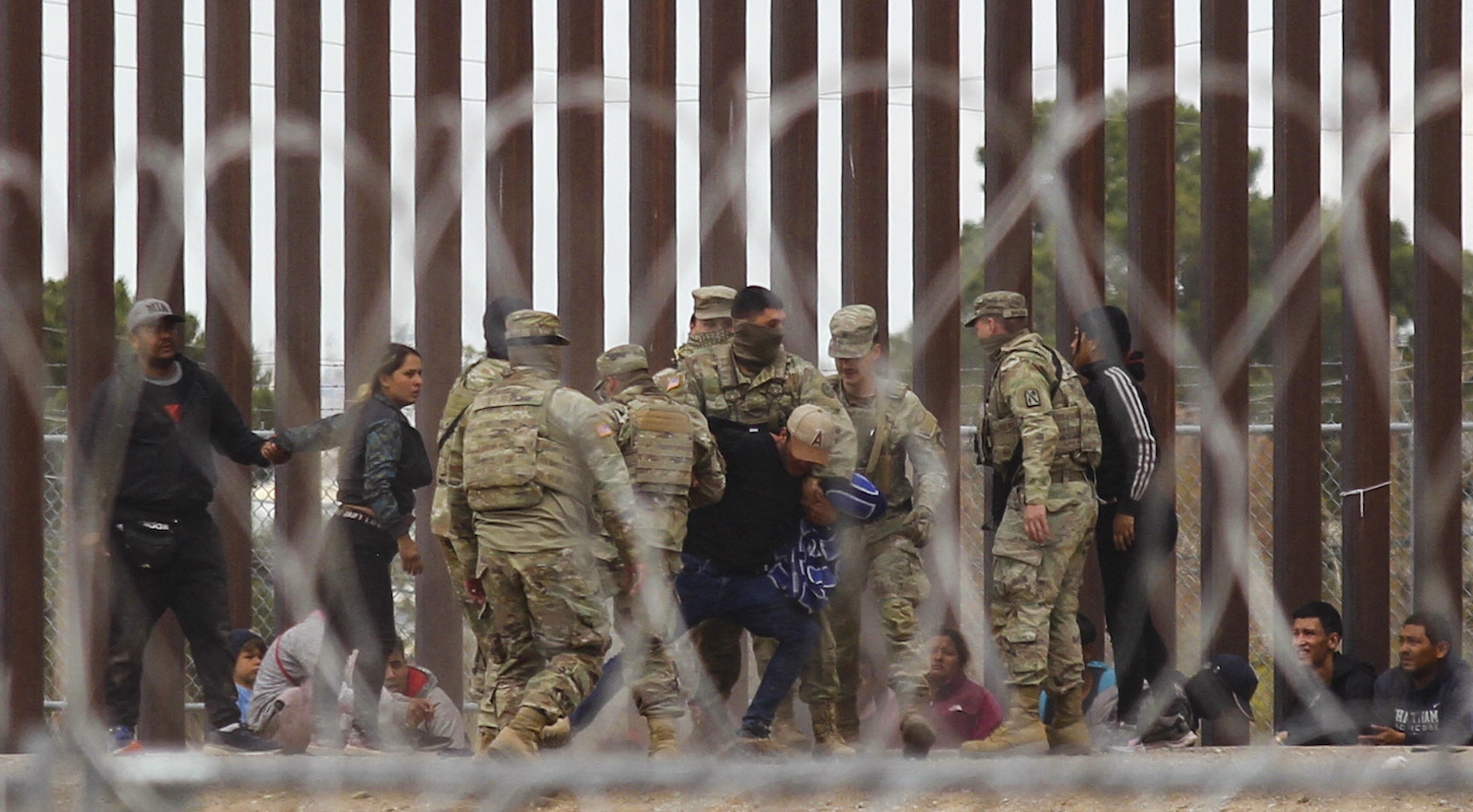 Agents of the Texas National Guard struggle with a migrant man after he crossed across the Rio Grande river to reach the US side, as seen from Ciudad Juarez, Mexico on March 20, 2024.