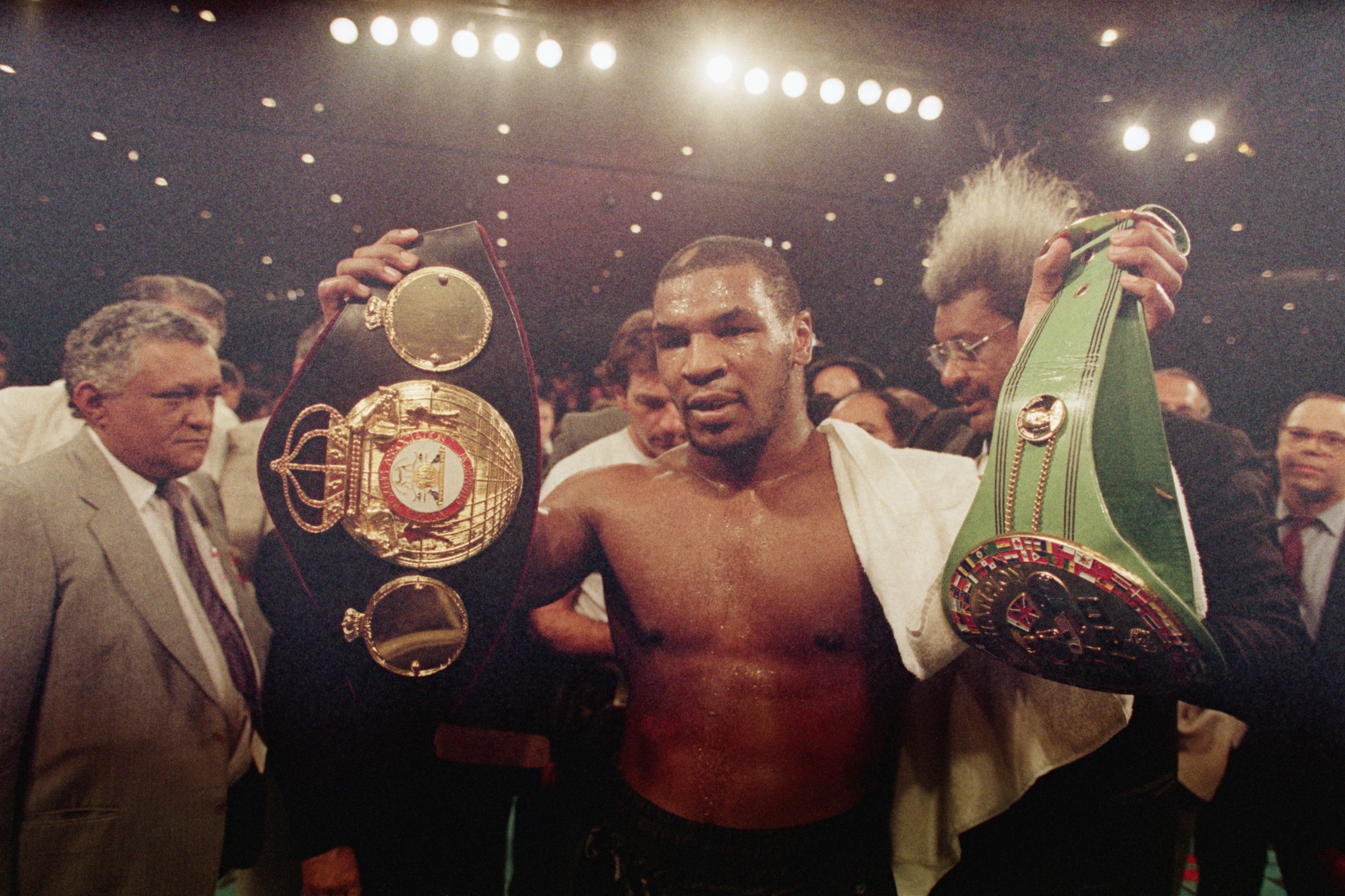 Mike Tyson holding his championship titles in the ring
