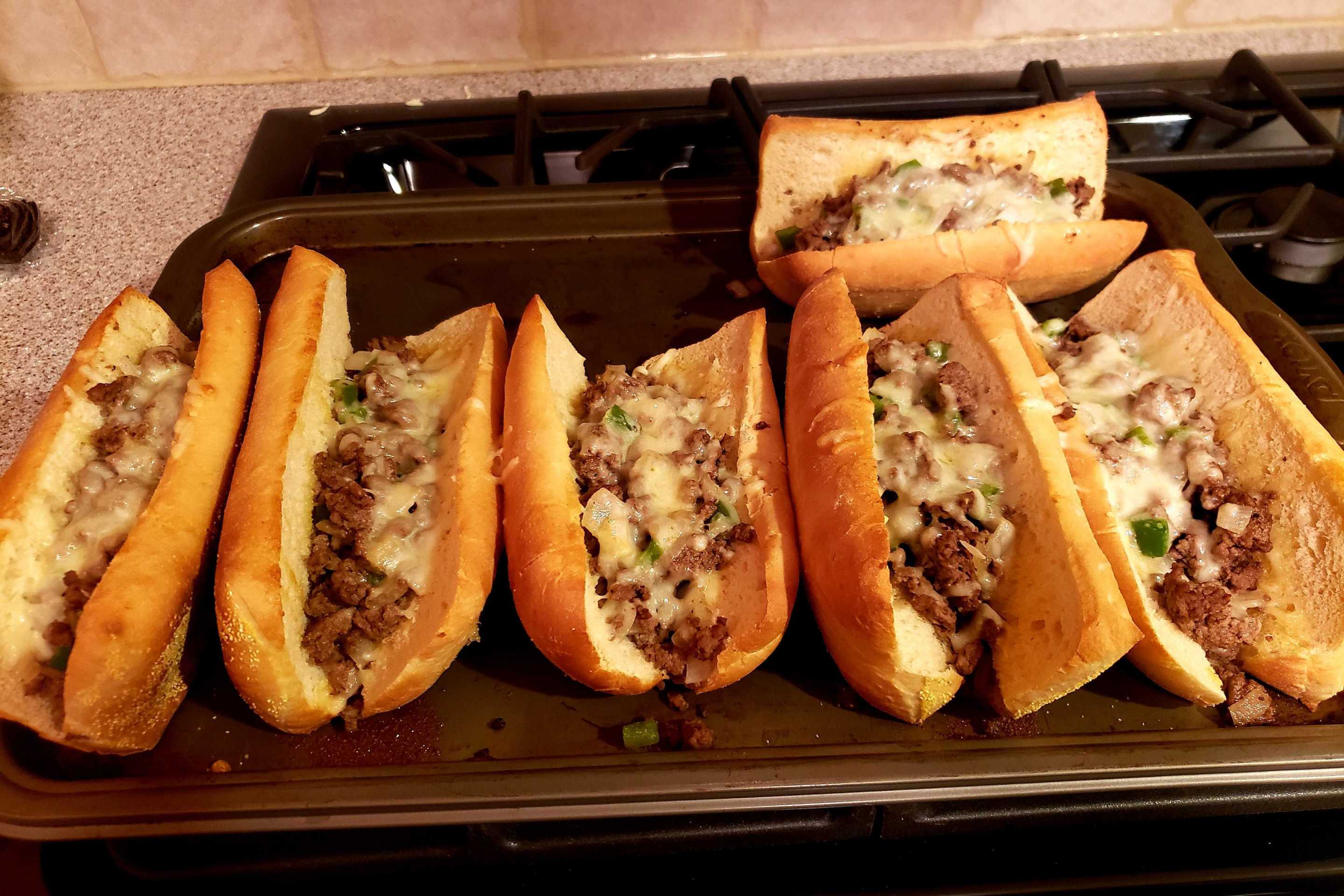 a set of homemade toasted subs with ground beef, cheese, green pepper and onion