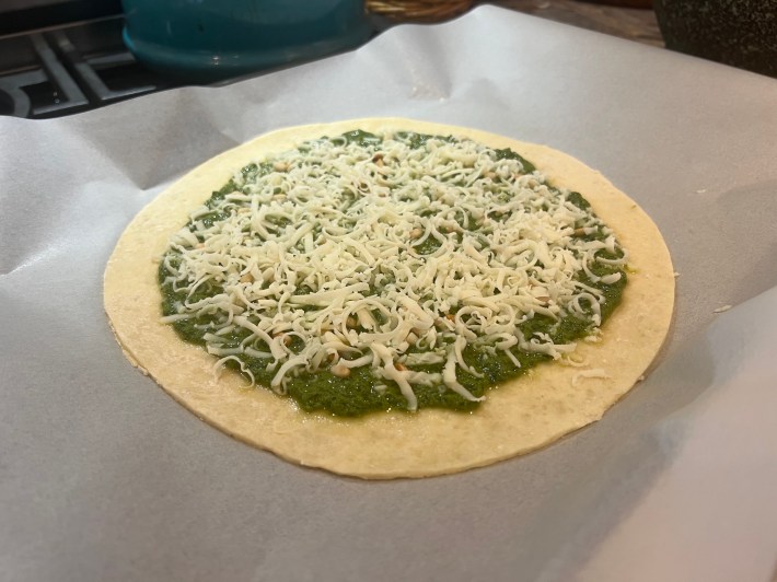 Pesto, pine nuts, and shredded mozzarella, on a circle of puff pastry.