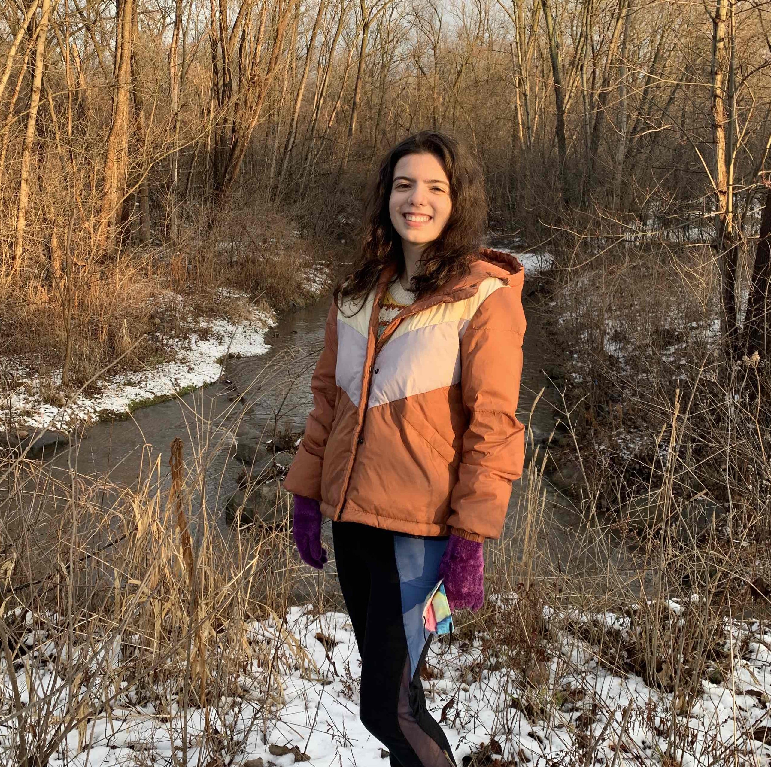 a photo of Veronica Correa, a fired EPA public affairs specialist, standing in snowy woods by a stream