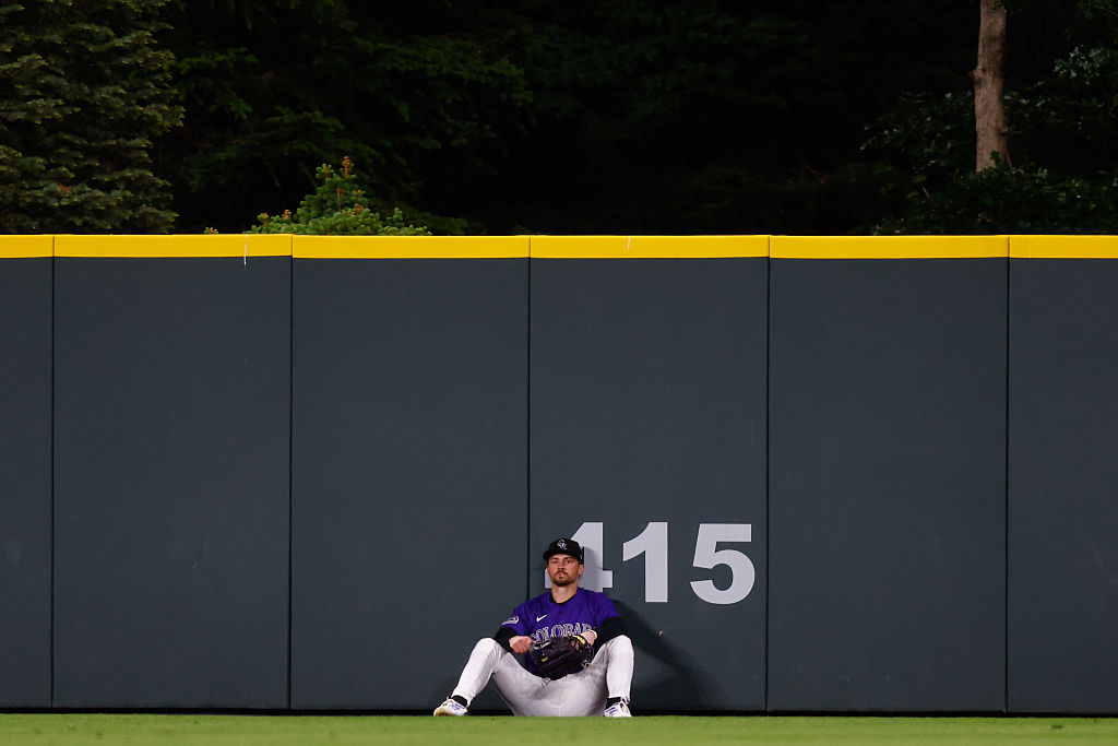 A dejected Brenton Doyle #9 of the Colorado Rockies sits on the ground after a go-ahead two run home run off the bat of Alec Bohm of the Philadelphia Phillies flew over his glove in the eighth inning at Coors Field on May 19, 2025 in Denver, Colorado.